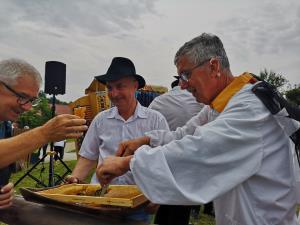 16. Čebelar Stane Barbo skupaj z voditeljem programa na Malem Kalu Leopoldom Pungerčarjem ponuja v pokušino čebelje satje.